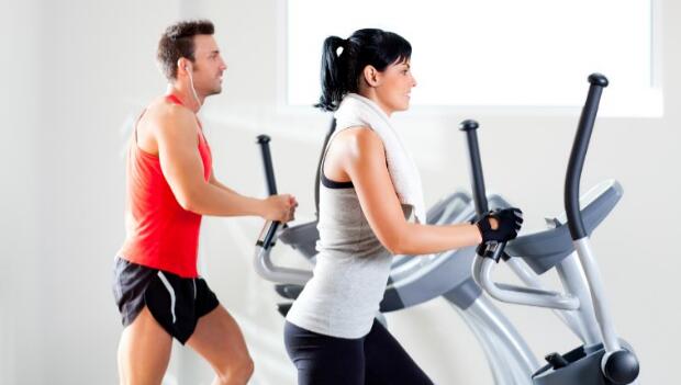 man and woman on elliptical machines