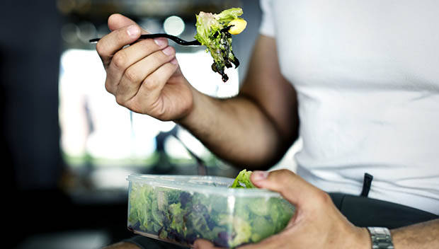 Person eating salad out of a container