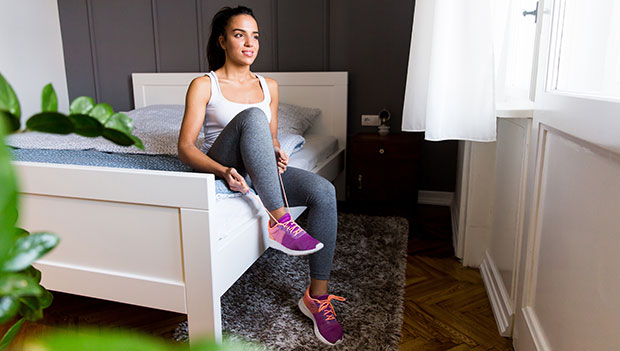 woman lacing her running shoes on the bed