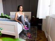 woman-lacing-her-running-shoes-on-the-bed-front