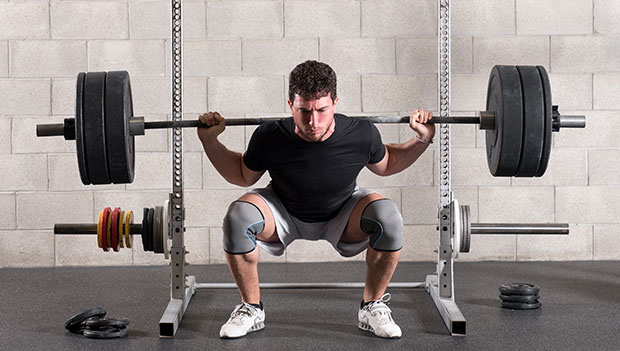 man using a barbell for squats