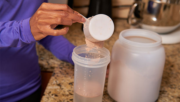 woman-scooping-protein-powder-into-a-shaker-bottle