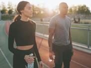 man-and-woman-holding-water-bottles-on-a-running-track