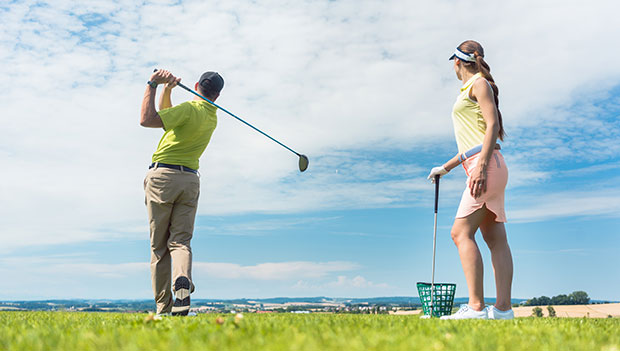 man and woman practicing golf swings