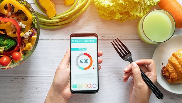 person-holding-a-fork-and-phone-with-daily-calories-listed