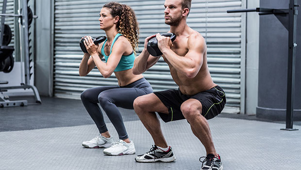 man and woman performing goblet squat with kettlebells