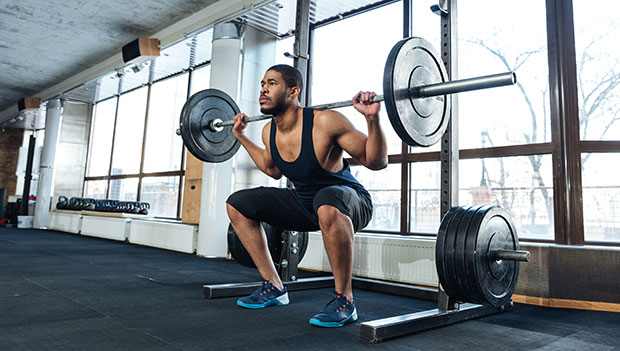 man squatting with barbell