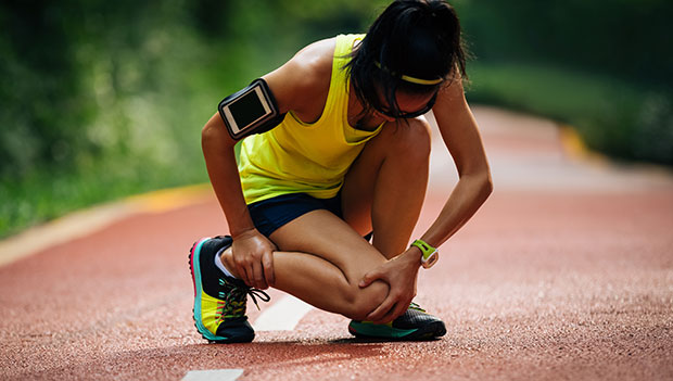 How-to-prevent-cramps-while-running_woman-stretching-on-track