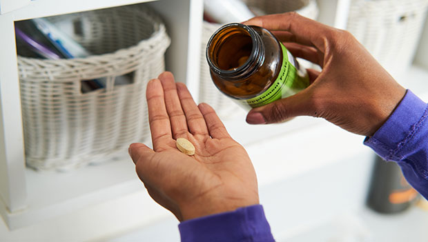 woman pouring pill into hand from bottle