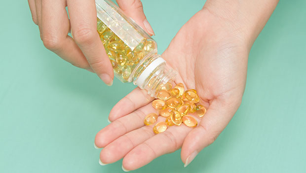 woman pouring vitamin e supplements into hand