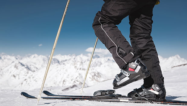 person wearing ski boot stepping into skis