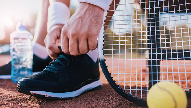 tying up tennis shoe on court