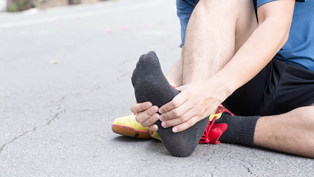 man -having-foot-pain-while-out-for-a-run-rubbing-his-heel-pain